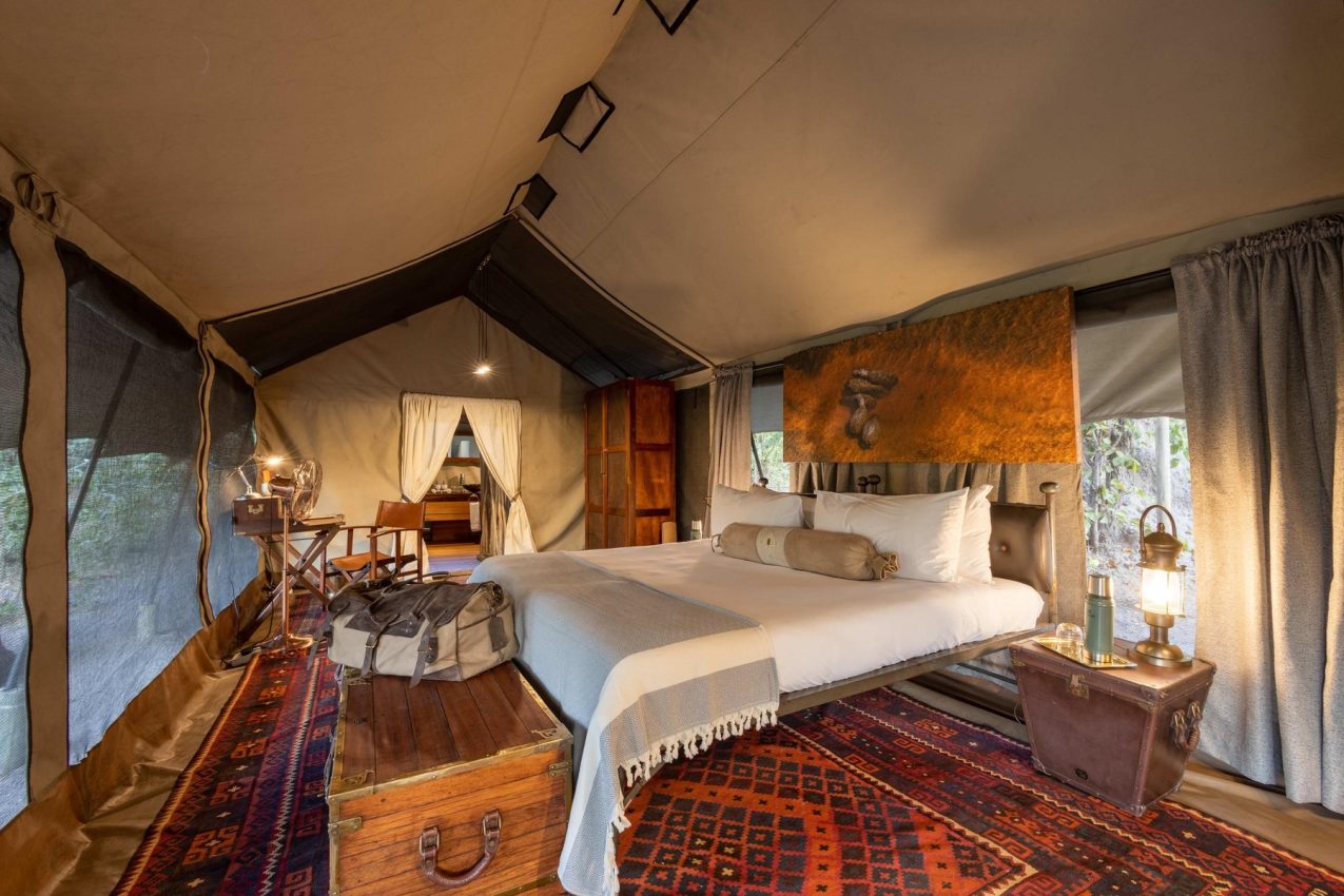 Luxury safari tent interior with canopy bed and warm lighting