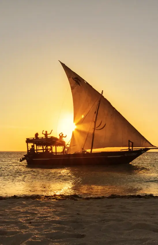 Traditional sailing dhow boat at sunset on ocean