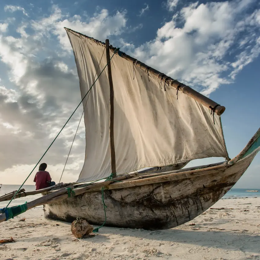 Traditional wooden sailing dhow beached on sandy shore