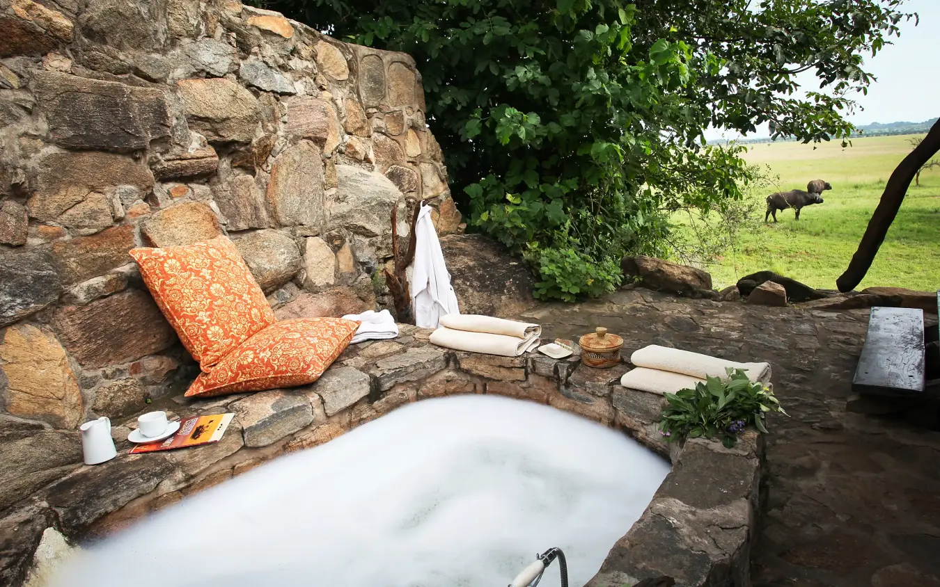 Outdoor bathtub with stone surround and safari views, Apoka Safari Lodge, Kidepo Valley, Uganda