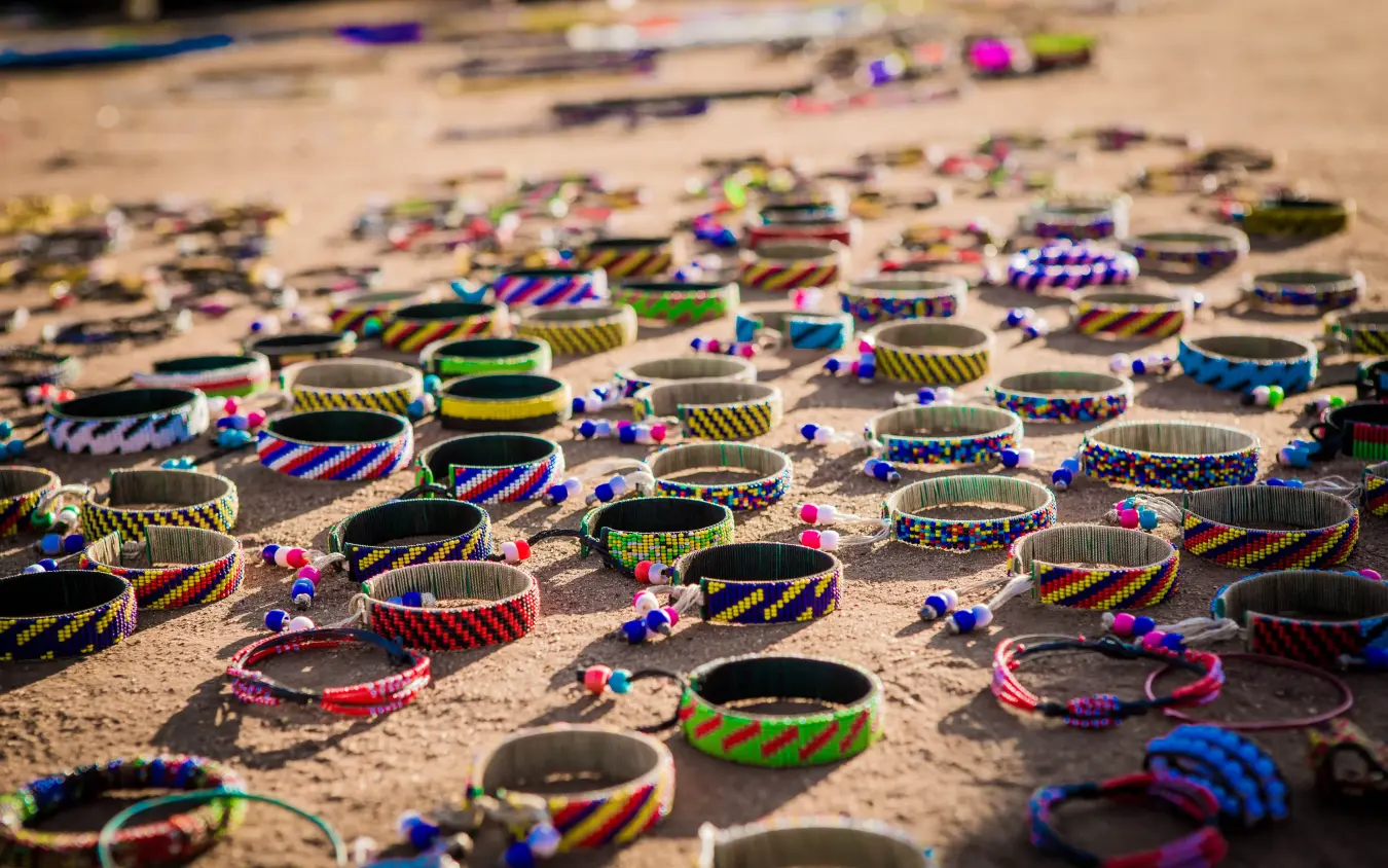 Colorful beaded bracelets and crafts arranged on sand, Apoka Safari Lodge, Kidepo Valley, Uganda