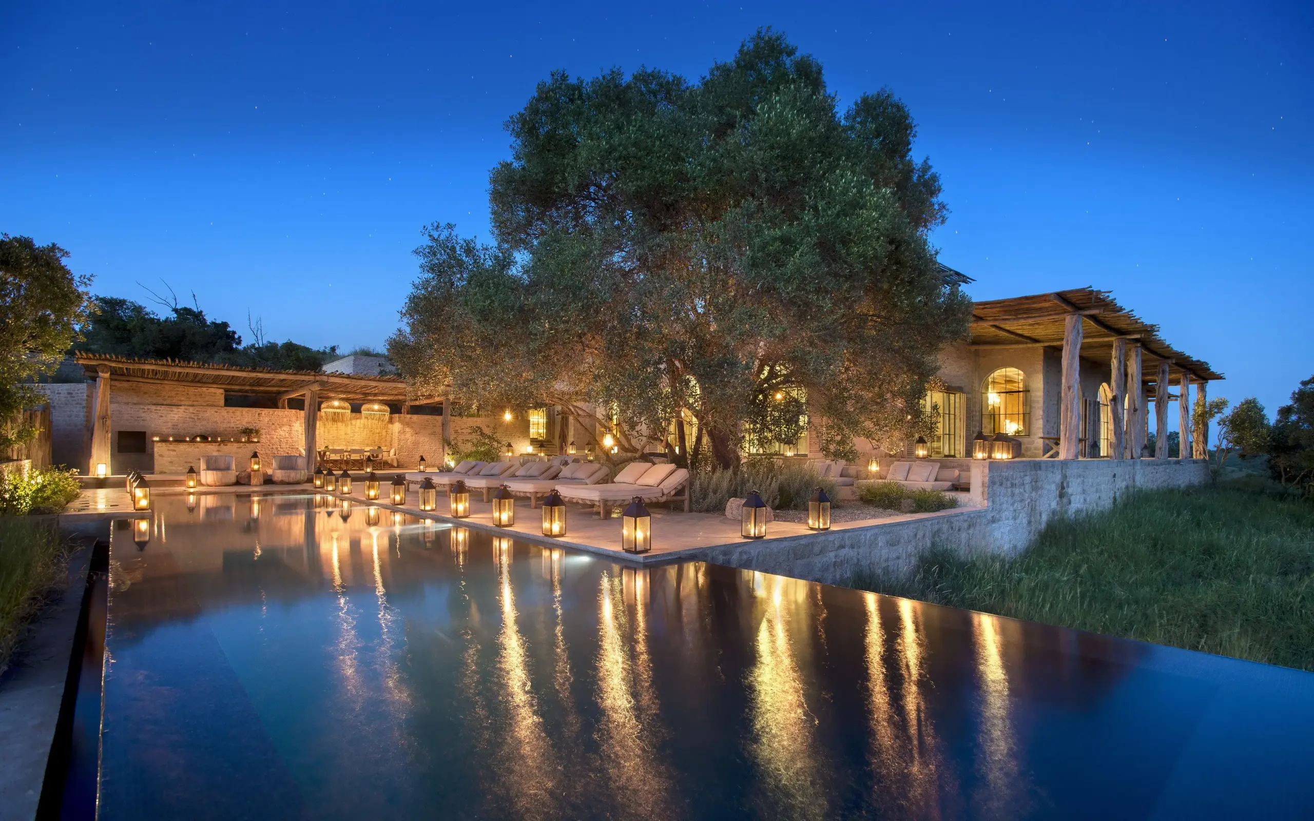 Illuminated lodge building reflected in still water at dusk, Arijiju, Laikipia Highlands, Kenya