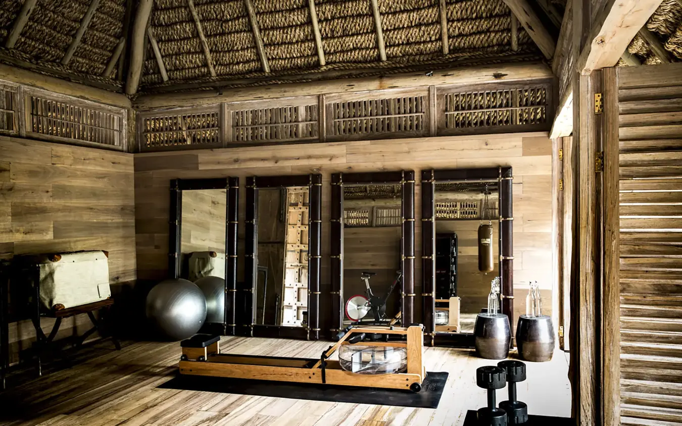 Wooden interior lounge with fitness equipment and mirrored closets, Arijiju, Laikipia Highlands, Kenya
