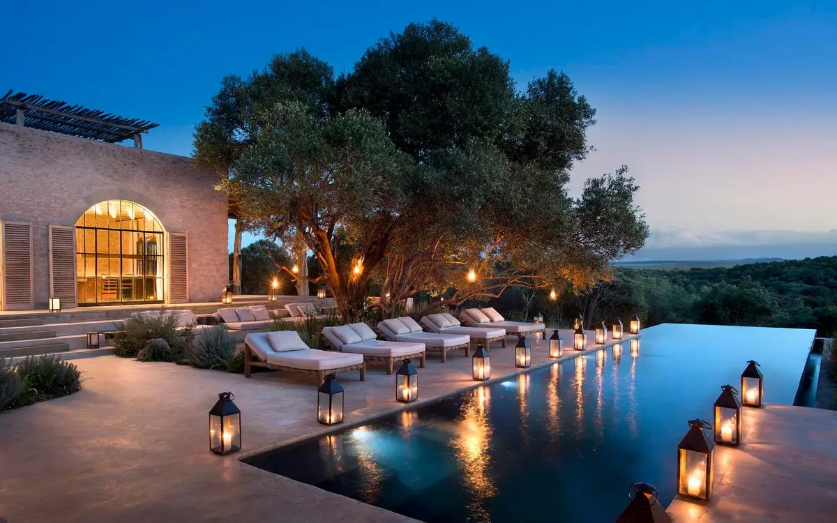 Illuminated infinity pool overlooking landscape at dusk, Arijiju, Laikipia Highlands, Kenya