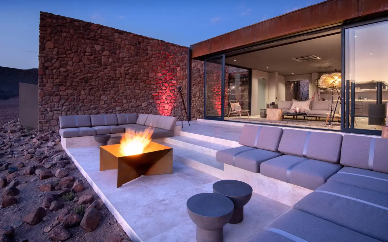 Desert lounge area with firepit and seating at dusk, Sossusvlei Desert Lodge, NamibRand Private Reserve, Namibia