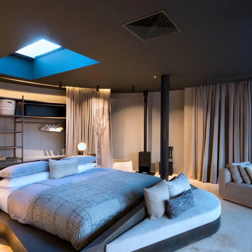 Modern bedroom with skylight, bed, lounge seating area, Sossusvlei Desert Lodge, NamibRand Private Reserve, Namibia