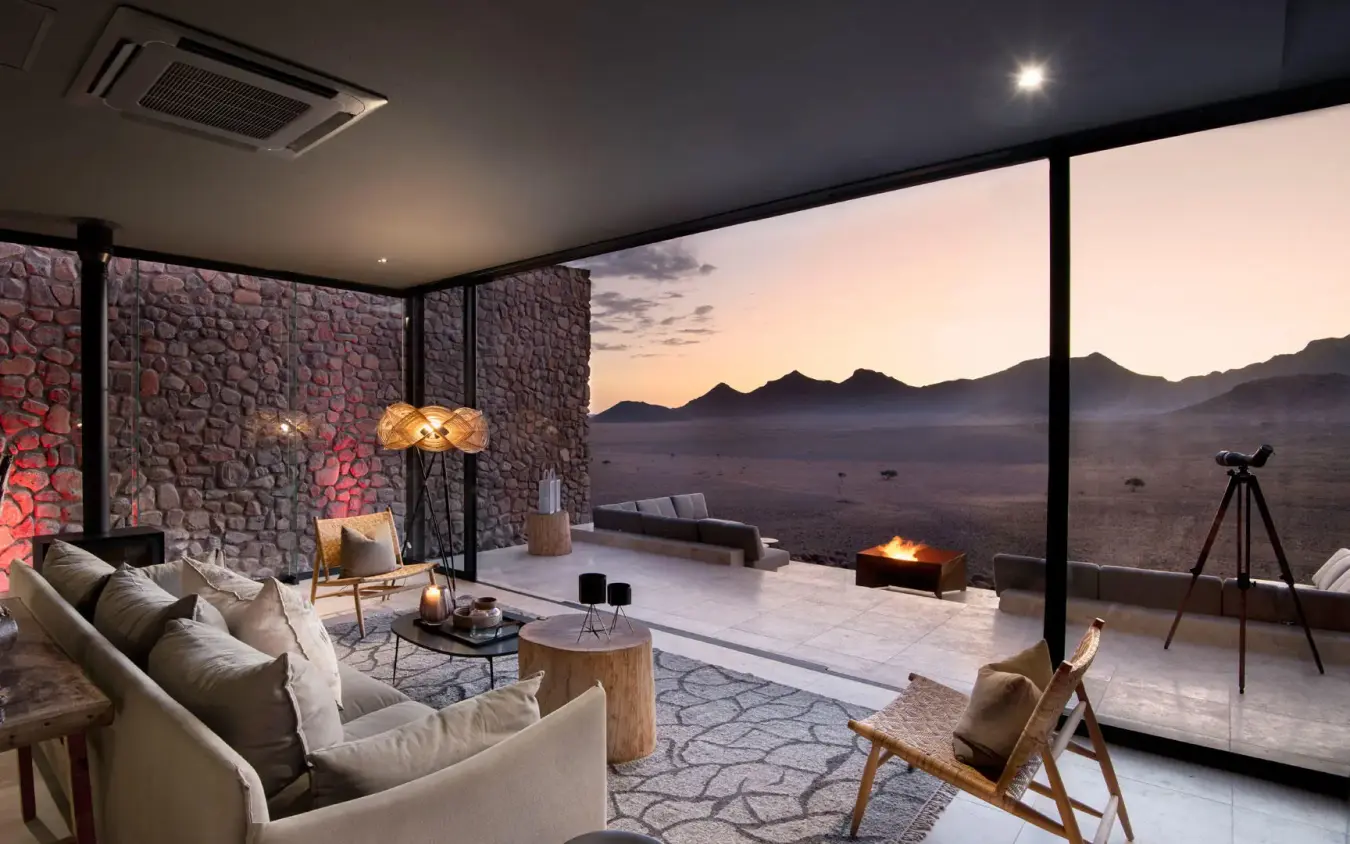 Modern lounge with floor-to-ceiling windows overlooking desert landscape, Sossusvlei Desert Lodge, NamibRand Private Reserve, Namibia