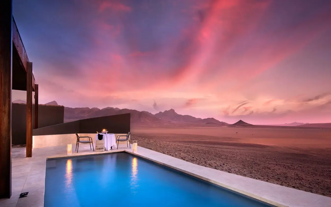 Infinity pool overlooking vast desert landscape at sunset, Sossusvlei Desert Lodge, NamibRand Private Reserve, Namibia