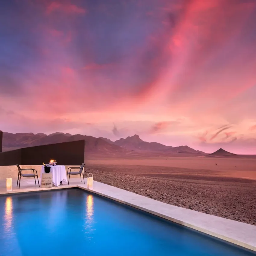 Infinity pool overlooking vast desert landscape at sunset, Sossusvlei Desert Lodge, NamibRand Private Reserve, Namibia
