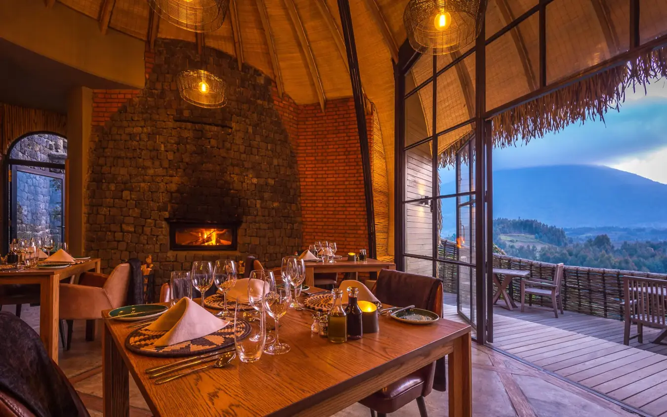 Fine dining room with fireplace overlooking volcanic mountain landscape, Bisate Lodge, Volcanoes National Park, Rwanda