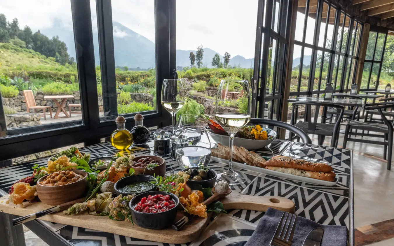 Fine dining table with food and wine overlooking volcanic landscape, Bisate Lodge, Volcanoes National Park, Rwanda