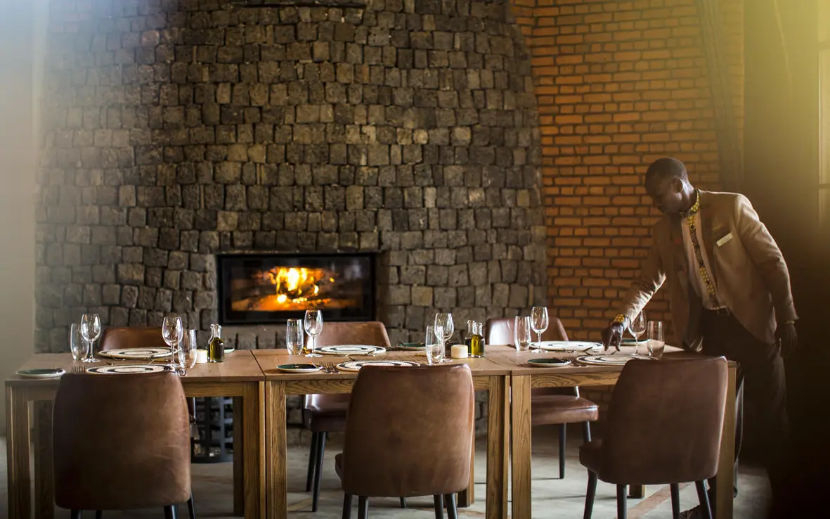 Fine dining room with fireplace and formally set table, Bisate Lodge, Volcanoes National Park, Rwanda