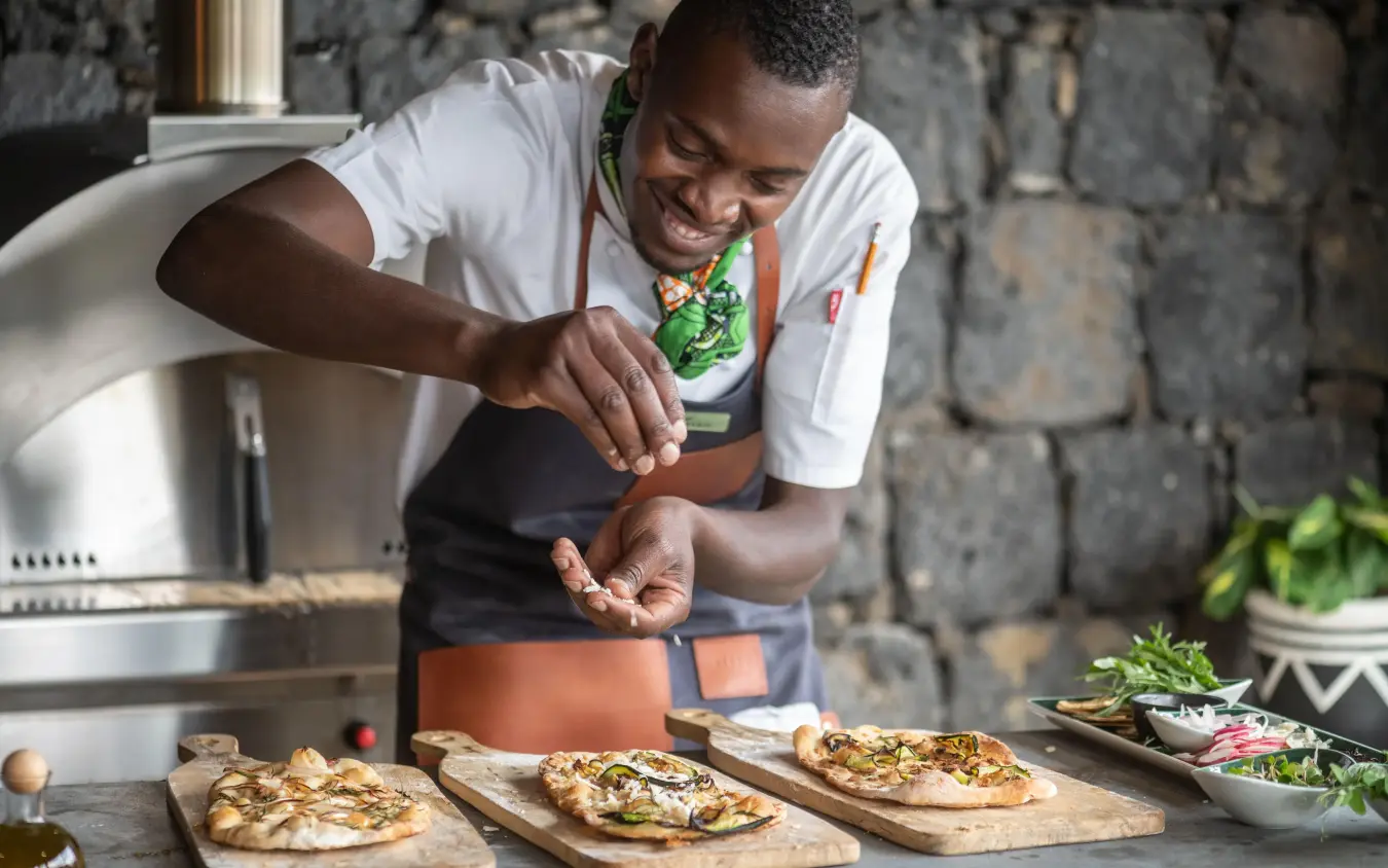 Chef preparing grilled flatbread with fresh vegetables outdoors, Bisate Lodge, Volcanoes National Park, Rwanda