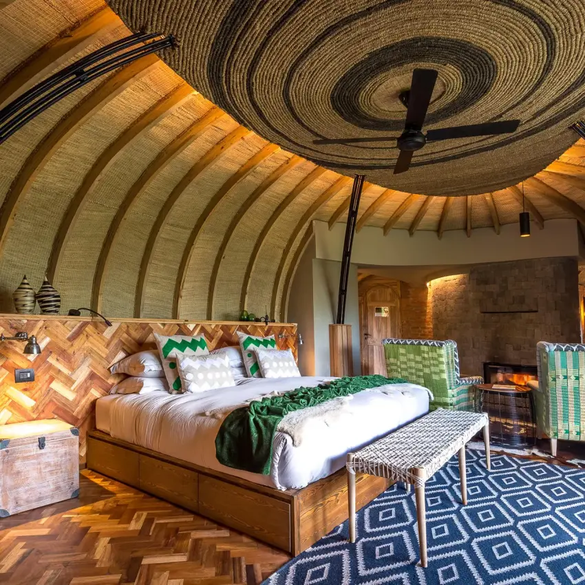 Barrel-vaulted bedroom with wooden bed and patterned rug, Bisate Lodge, Volcanoes National Park, Rwanda