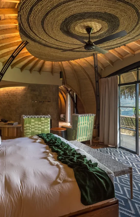 Luxury bedroom with curved wooden ceiling and terrace view, Bisate Lodge, Volcanoes National Park, Rwanda