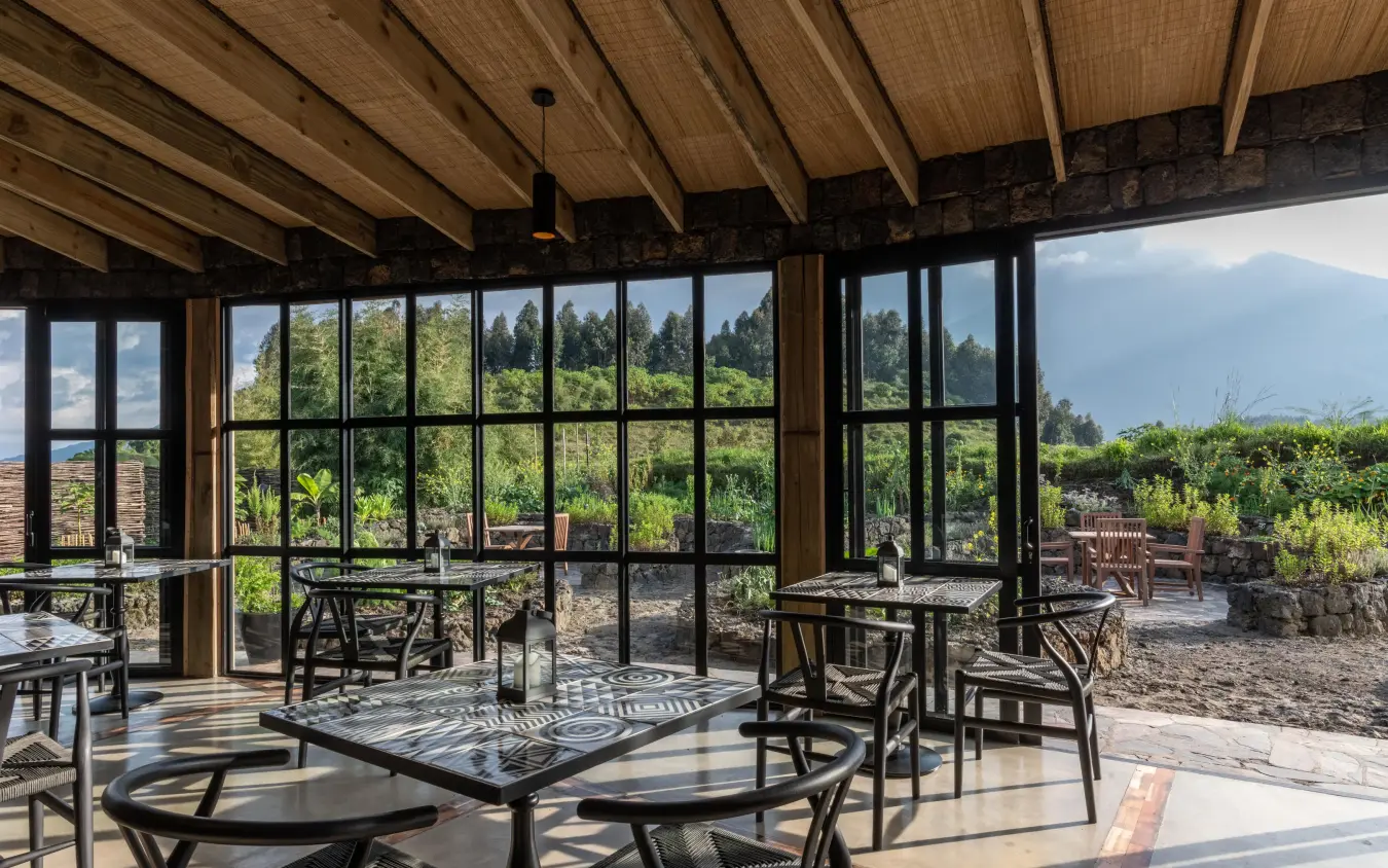 Interior dining space with expansive windows overlooking green landscape, Bisate Lodge, Volcanoes National Park, Rwanda