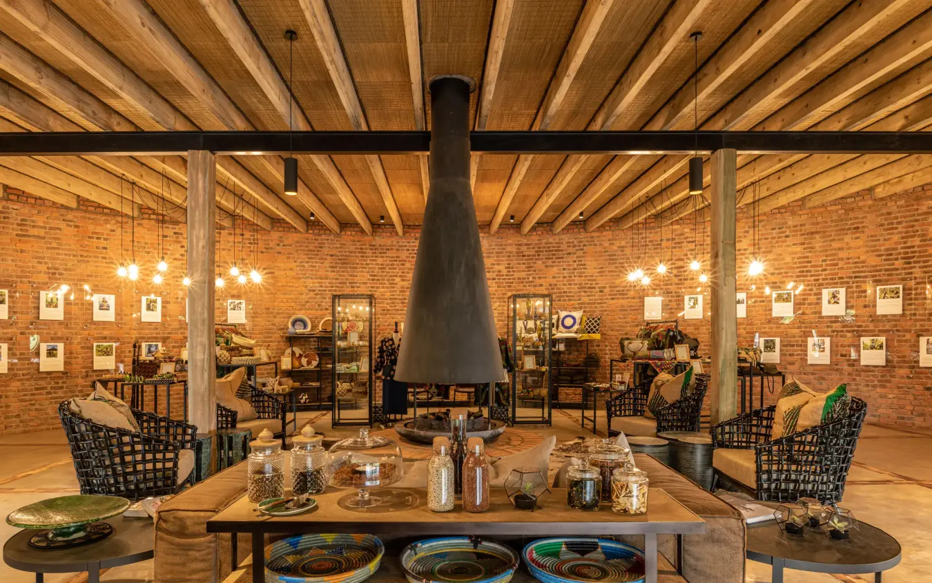 Interior lounge with central fireplace and exposed wooden beams, Bisate Lodge, Volcanoes National Park, Rwanda