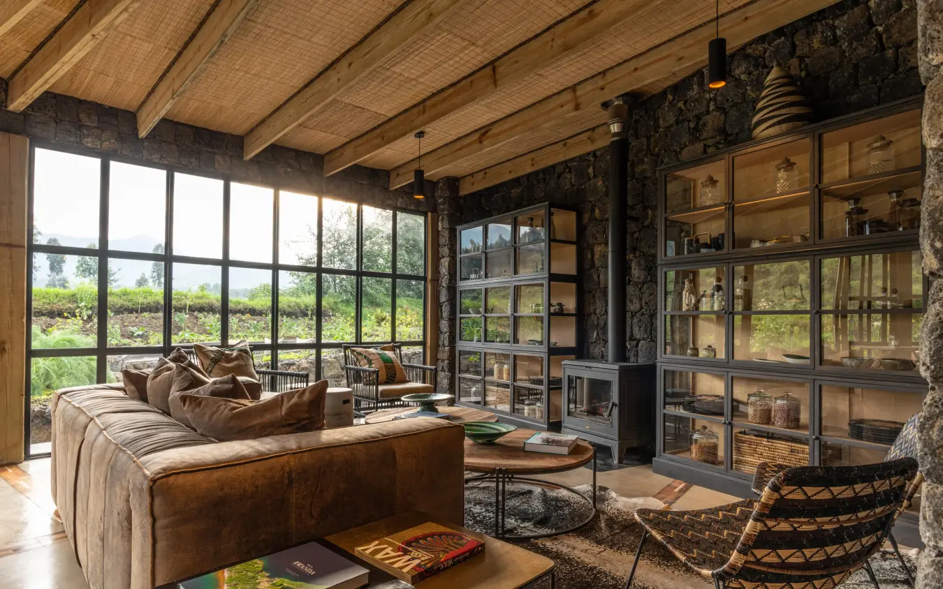 Modern lounge with floor-to-ceiling windows overlooking green landscape, Bisate Lodge, Volcanoes National Park, Rwanda