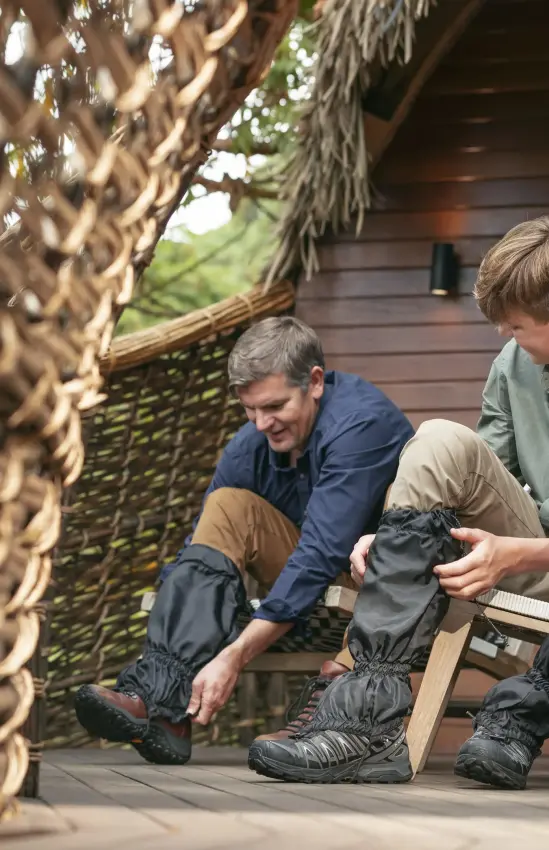 Two guests sitting on deck examining hiking boots together, Volcanoes National Park, Rwanda