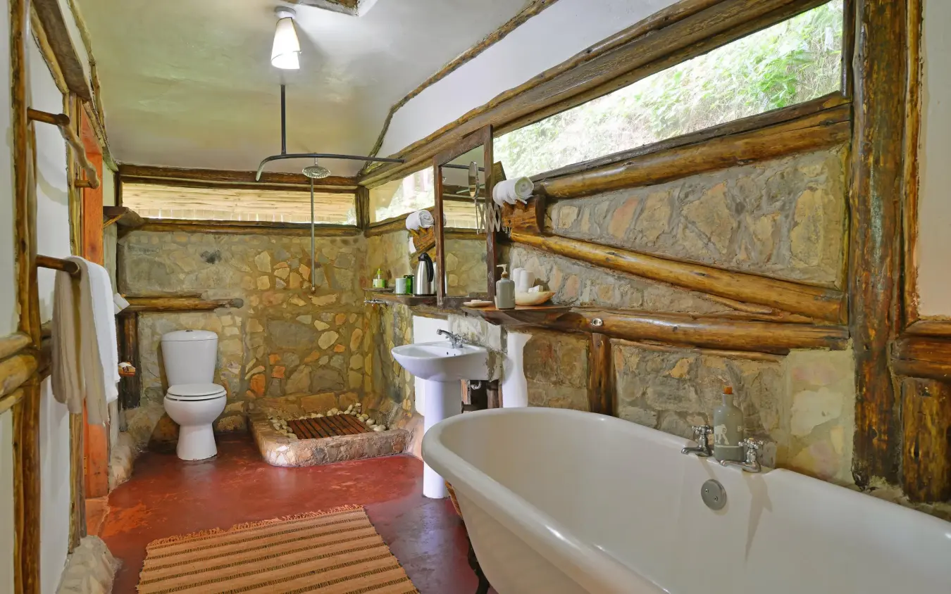 Rustic bathroom with stone walls and soaking tub, Buhoma Lodge, Bwindi Impenetrable Forest, Uganda