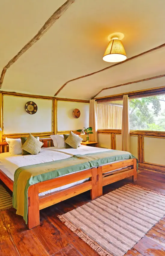 Wooden canopy bed in bright bedroom with veranda views, Buhoma Lodge, Bwindi Impenetrable Forest, Uganda