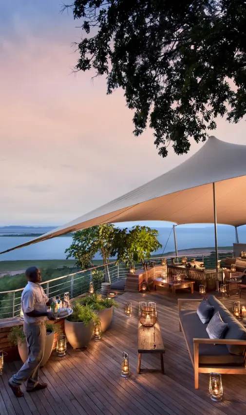 Elevated deck overlooking lake at dusk with dining setup, Bumi Hills Safari Lodge, Matusadona National Park, Zimbabwe