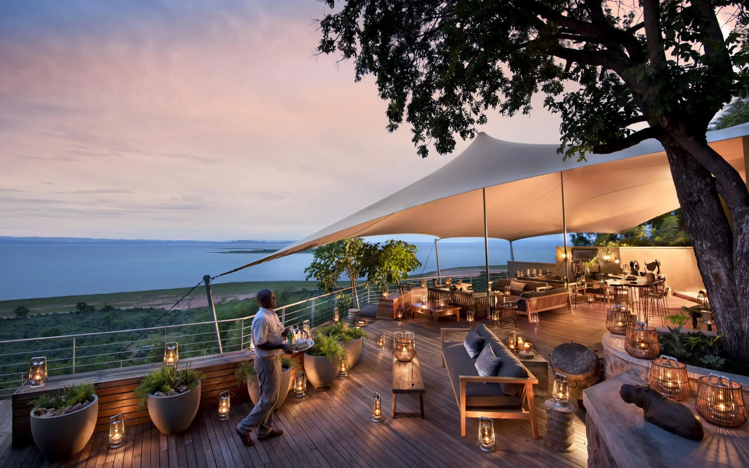 Elevated deck overlooking lake at dusk with dining setup, Bumi Hills Safari Lodge, Matusadona National Park, Zimbabwe