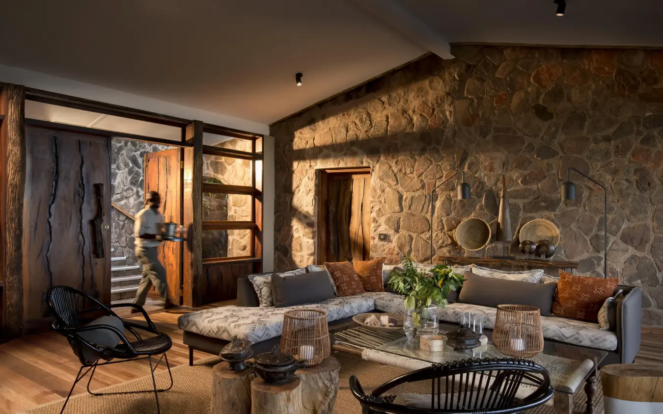 Stone-walled lounge with seating and glass doors at dusk, Bumi Hills Safari Lodge, Matusadona National Park, Zimbabwe