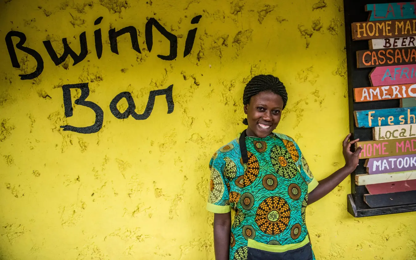 Staff member smiling in front of Bwindi Bar sign, Bwindi Lodge, Bwindi Impenetrable Forest, Uganda