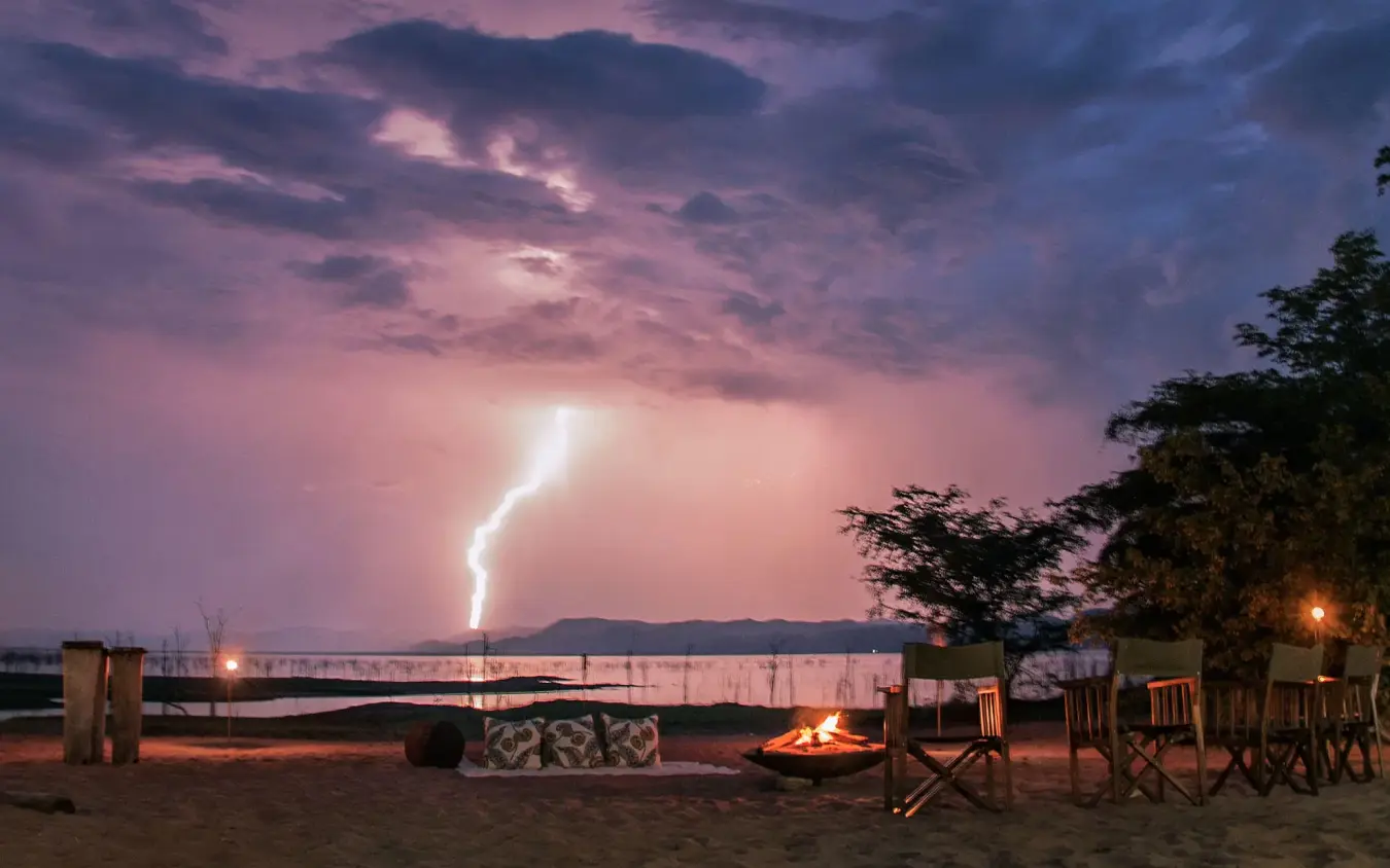 Beachside camp setup with lightning storm at dusk, Changa Safari Camp, Matusadona National Park, Zimbabwe
