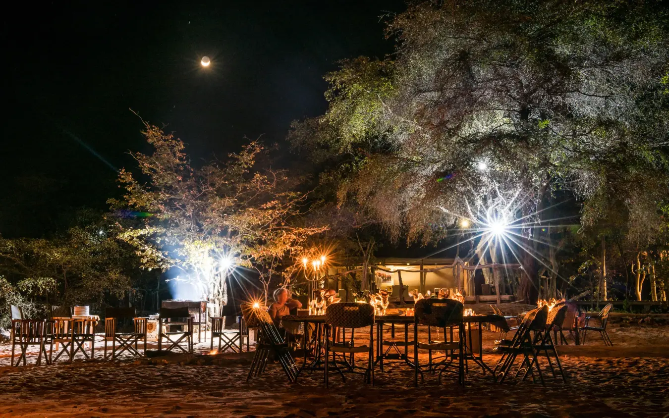 Outdoor dining area at night under moonlight with trees, Changa Safari Camp, Matusadona National Park, Zimbabwe