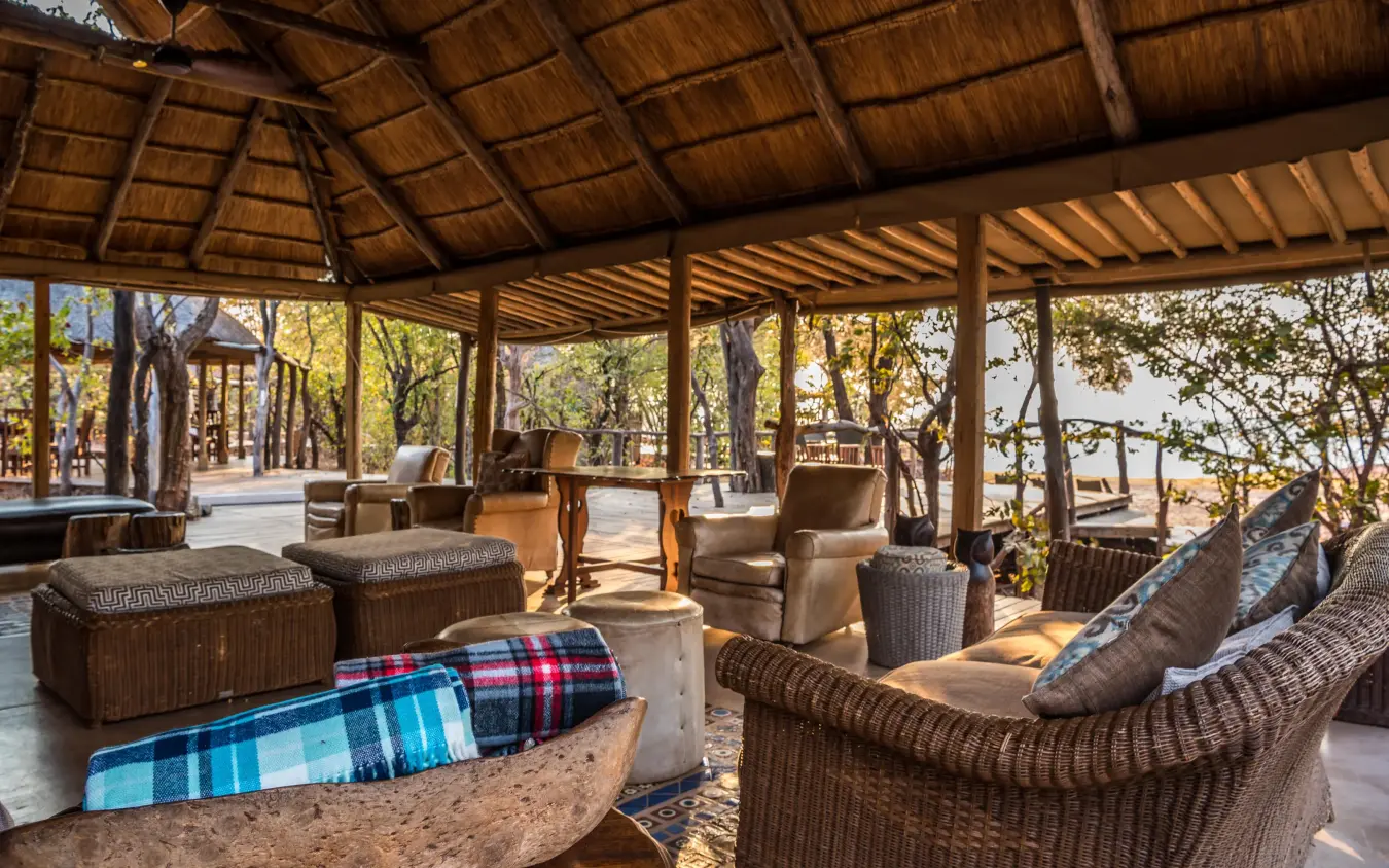 Thatched lounge pavilion with wicker seating and forest views, Changa Safari Camp, Matusadona National Park, Zimbabwe