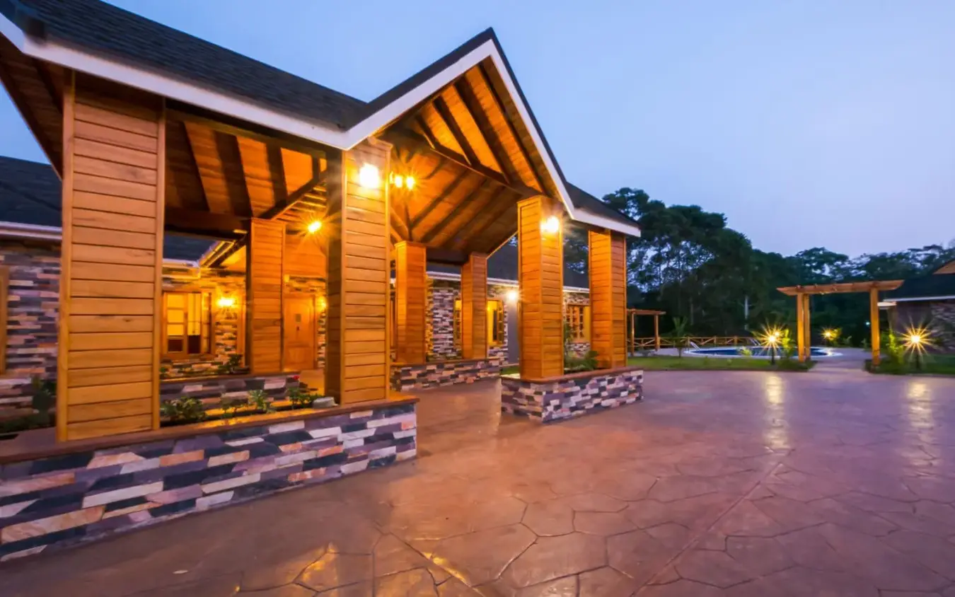 Modern lodge exterior with lit wooden architecture at dusk, Chimpundu Lodge, Kibale Forest, Uganda