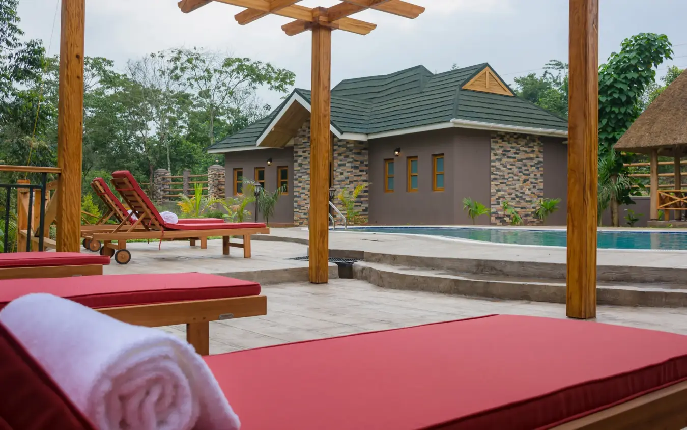 Poolside lounge area with wooden pergola and guest lodge, Chimpundu Lodge, Kibale Forest, Uganda