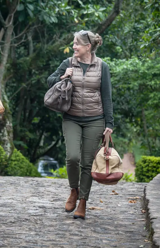 Two women walking on stone path through lush green forest, Clouds Mountain Gorilla Lodge, Bwindi Impenetrable Forest, Uganda