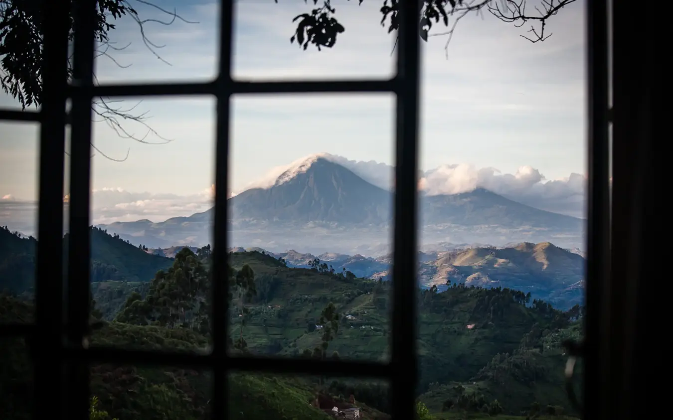 Snow-capped volcano viewed through window with green valleys, Clouds Mountain Gorilla Lodge, Bwindi Impenetrable Forest, Uganda
