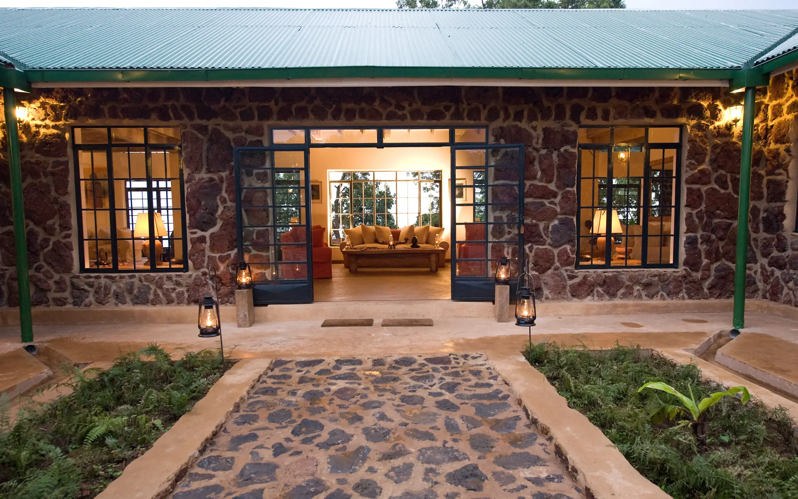 Stone lodge entrance with courtyard at dusk, Clouds Mountain Gorilla Lodge, Bwindi Impenetrable Forest, Uganda
