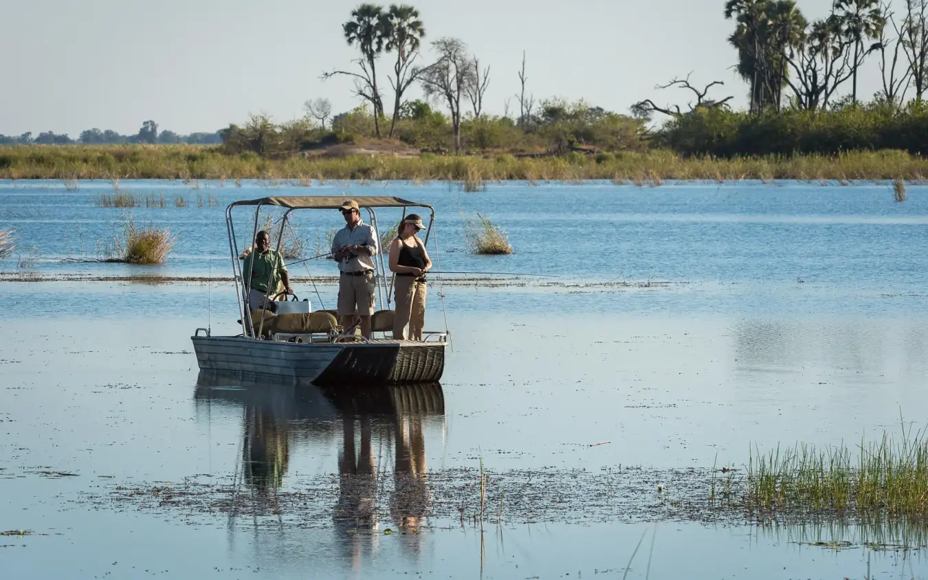 Guests on motorboat in shallow water delta landscape, DumaTau, Linyanti Wildlife Reserve, Botswana