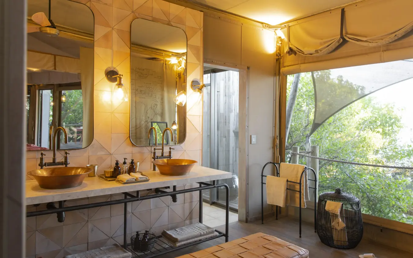 Luxury bathroom with dual copper sinks and forest views, DumaTau, Linyanti Wildlife Reserve, Botswana