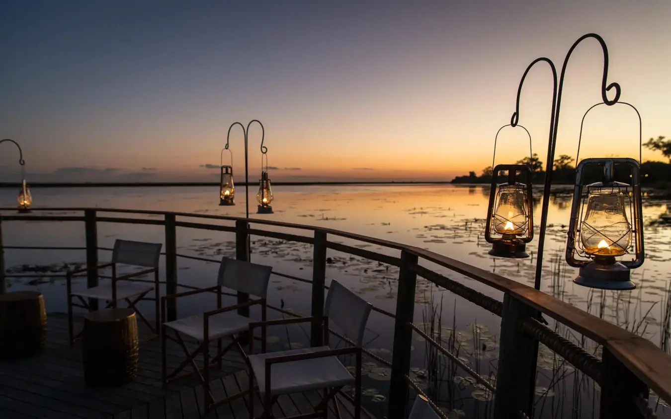 Waterside deck at sunset with hanging lanterns and chairs, DumaTau, Linyanti Wildlife Reserve, Botswana
