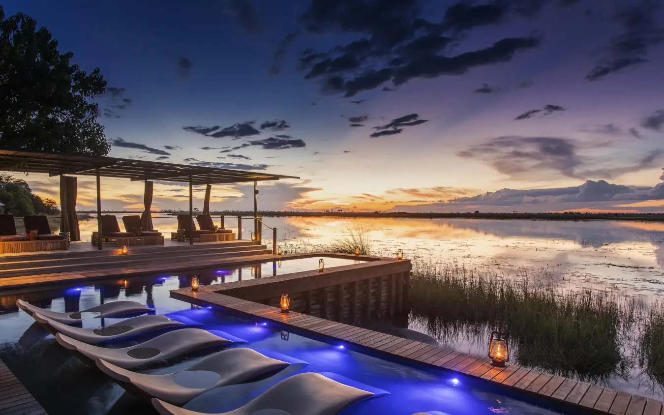 Waterfront deck with lounge chairs overlooking flooded plains at dusk, DumaTau, Linyanti Wildlife Reserve, Botswana