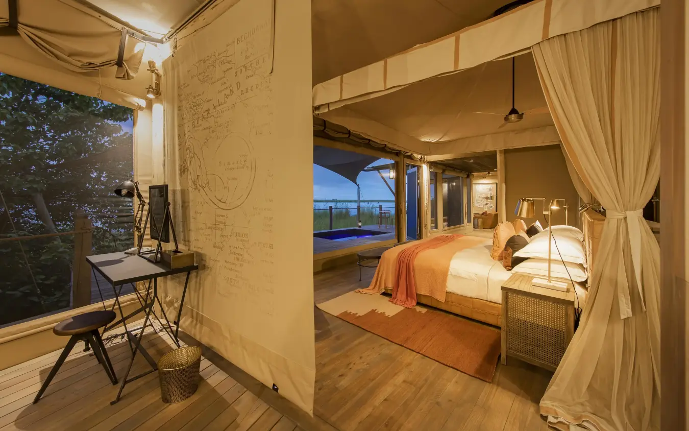 Luxury bedroom with draped canopy overlooking water at dusk, DumaTau, Linyanti Wildlife Reserve, Botswana