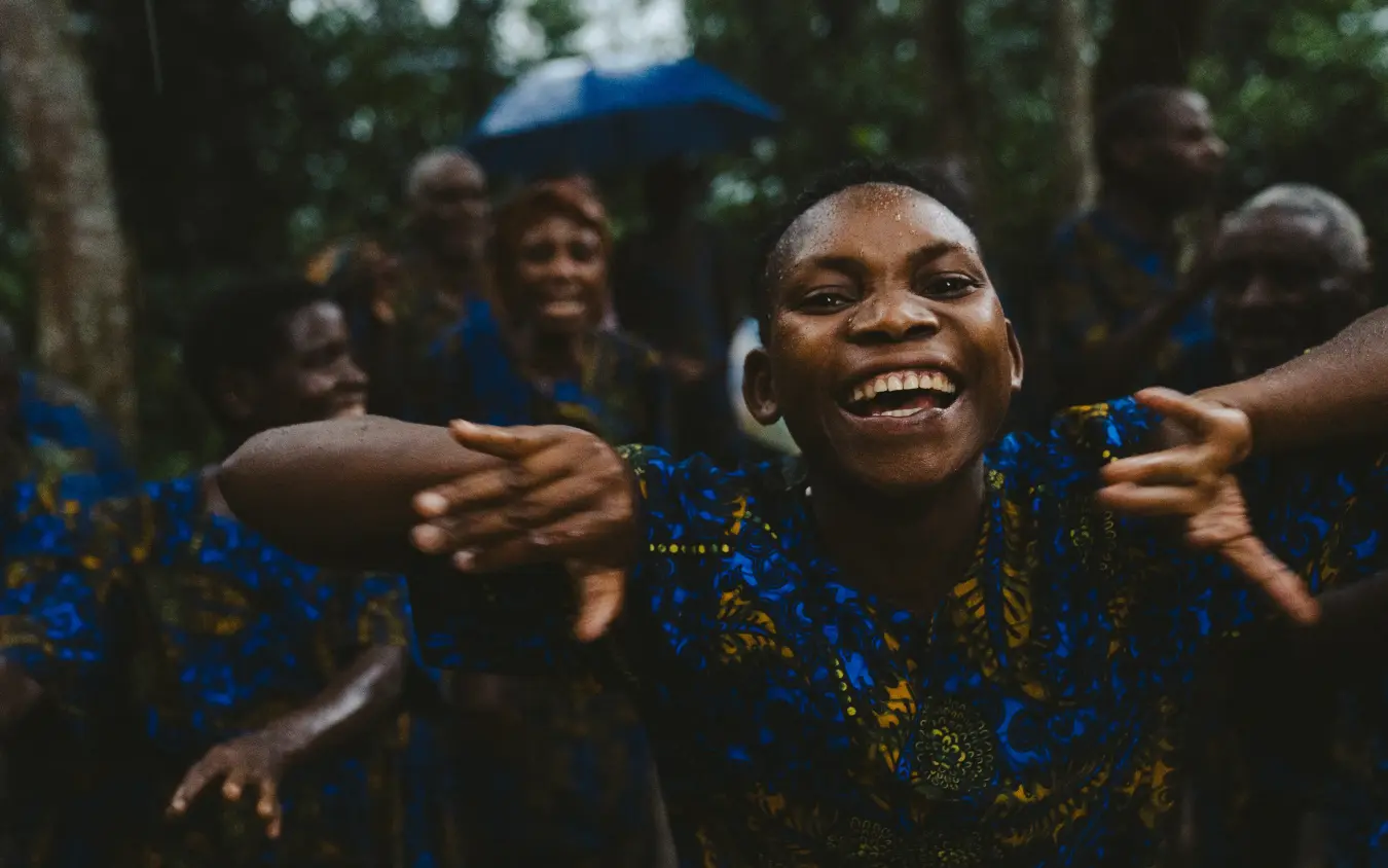 Group of people in patterned clothing smiling together outdoors, Gorilla Forest Lodge, Bwindi Impenetrable Forest, Uganda