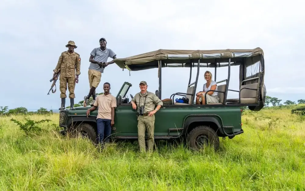 safari vehicle with guides and tourists in grassland, Honey Bear Bush Camp, Queen Elizabeth NP, Uganda