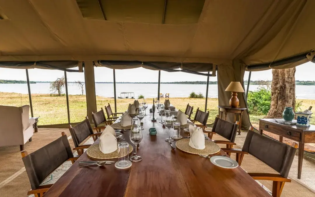 Long dining table with place settings overlooking water, Honey Bear Bush Camp, Queen Elizabeth NP, Uganda