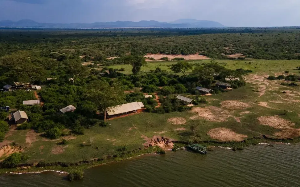 Aerial view of riverside camp with forest and waterway, Honey Bear Bush Camp, Queen Elizabeth NP, Uganda