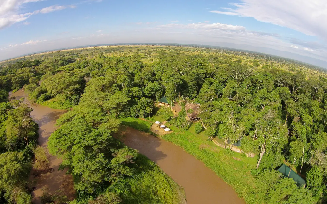 Aerial view of riverside lodge nestled in dense forest canopy, Ishasha Wilderness Camp, Queen Elizabeth NP, Uganda