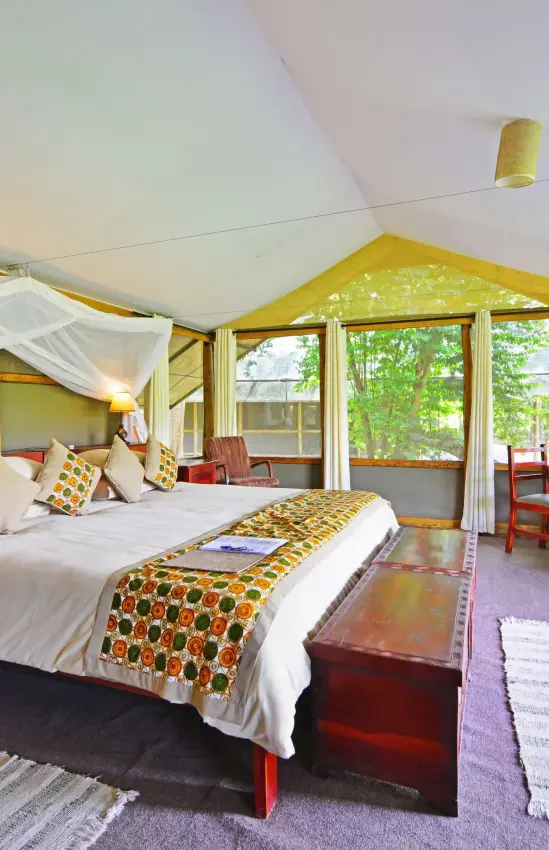 Spacious bedroom with canopy bed and large windows overlooking grounds, Ishasha Wilderness Camp, Queen Elizabeth NP, Uganda