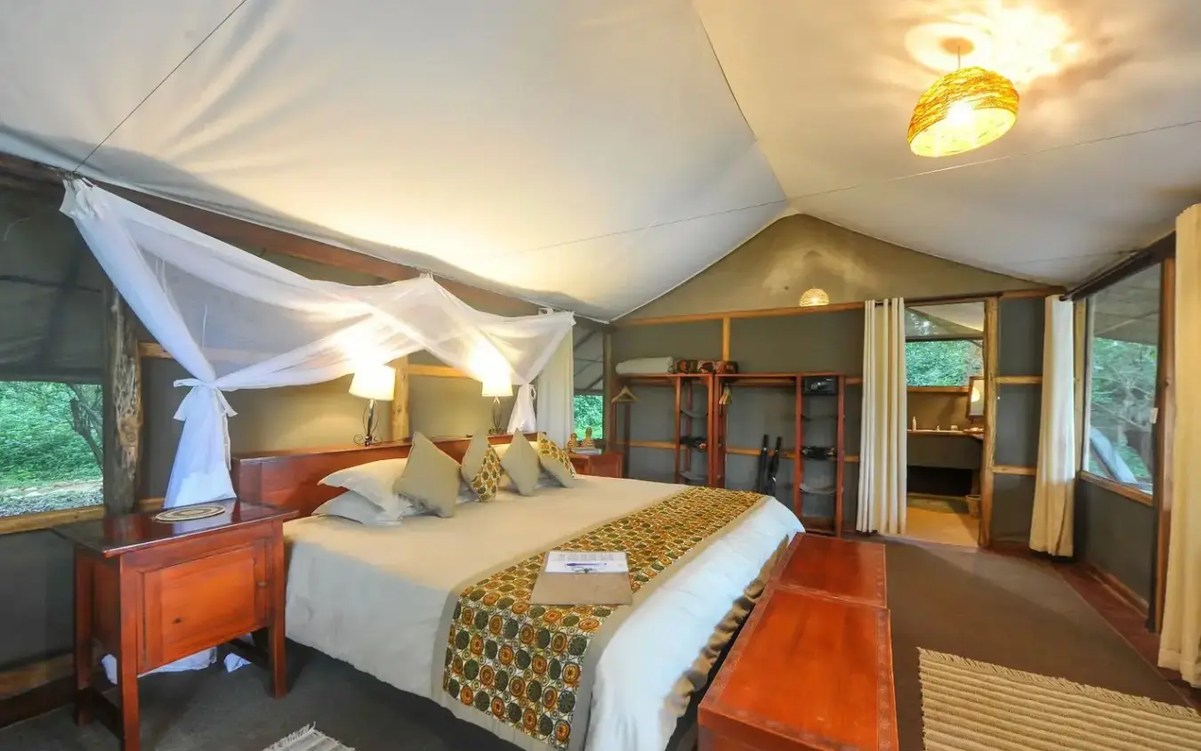 Luxury safari tent bedroom with four-poster bed and windows, Ishasha Wilderness Camp, Queen Elizabeth NP, Uganda