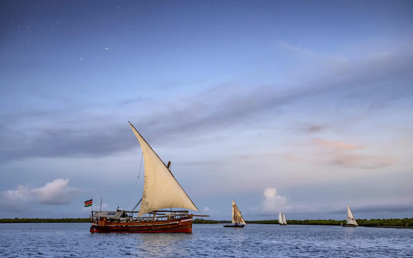 Traditional sailing dhow with smaller boats on calm water, Tusitiri Dhow, Lamu Archipelago, Kenya